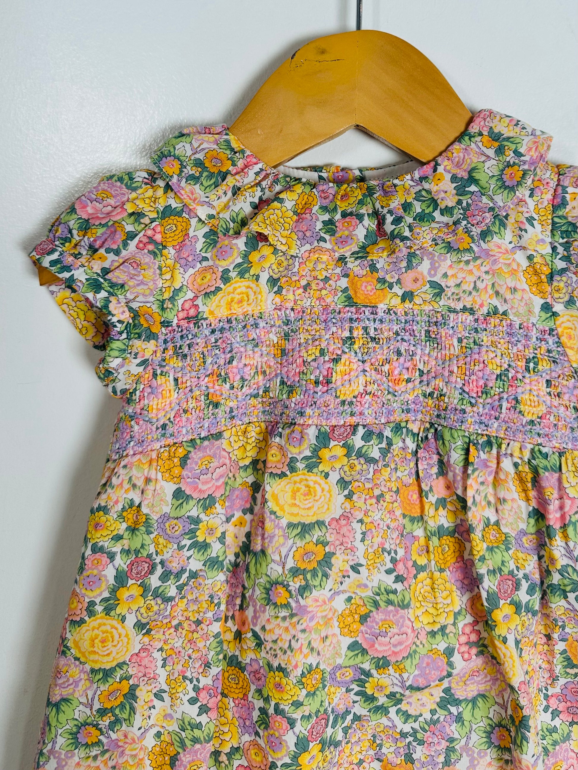Floral dress on a wooden hanger against a white background