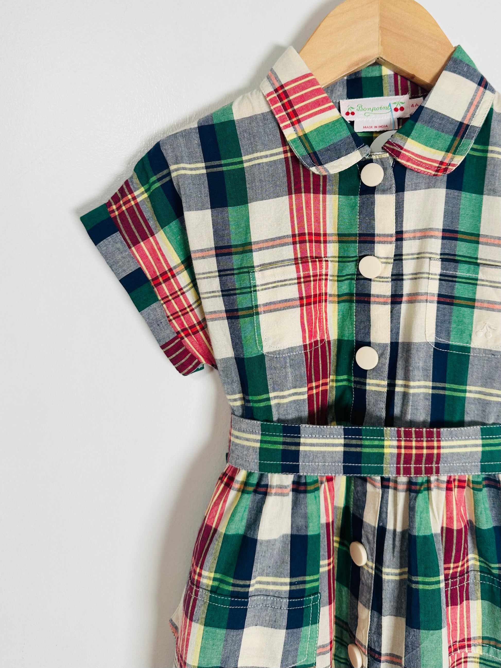 Plaid baby romper on a hanger against a white background