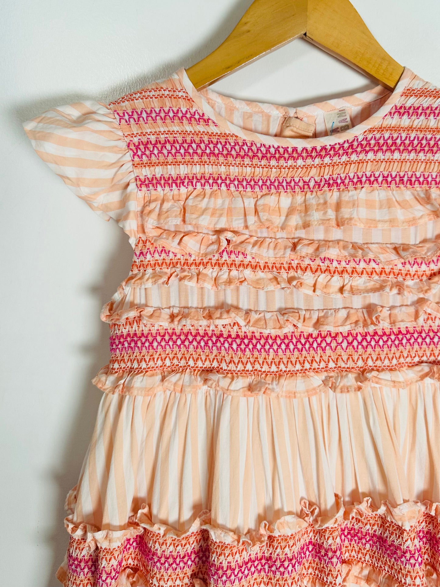 Multicolored patterned dress on a hanger against a white background