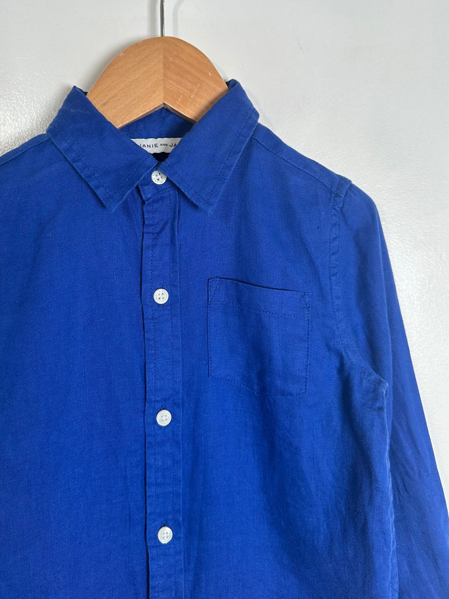 Blue shirt on a wooden hanger against a white background