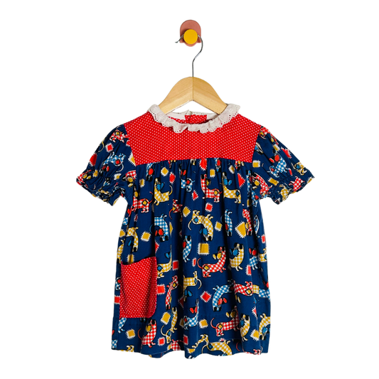 Children's dress with red collar and colorful pattern on a hanger against a white background