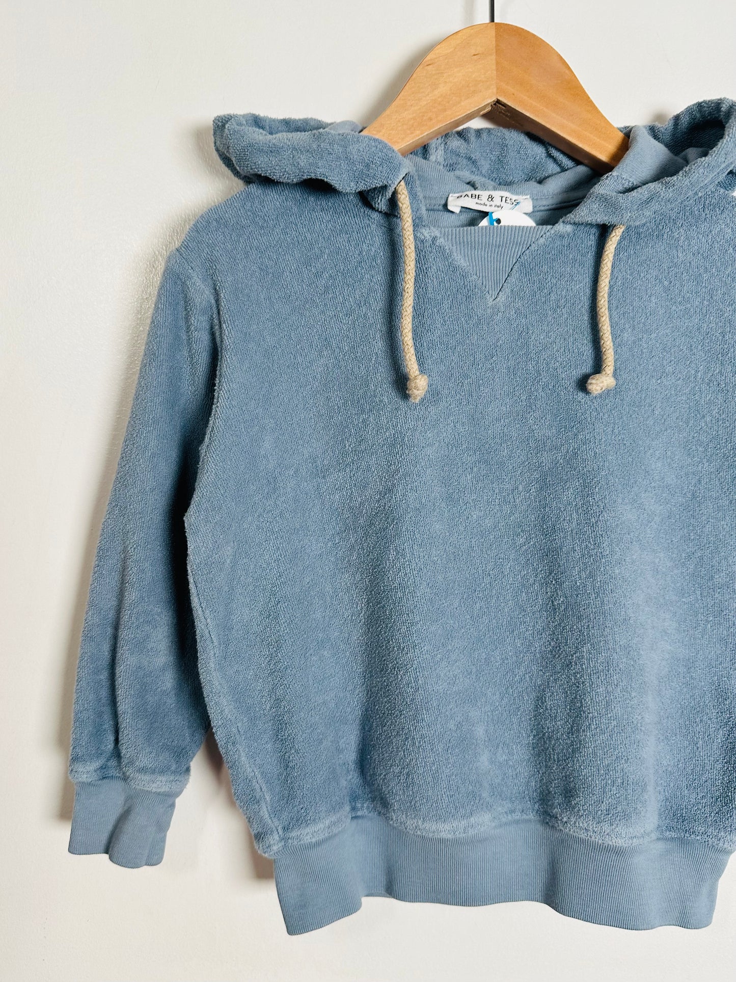Blue hoodie on a wooden hanger against a white background
