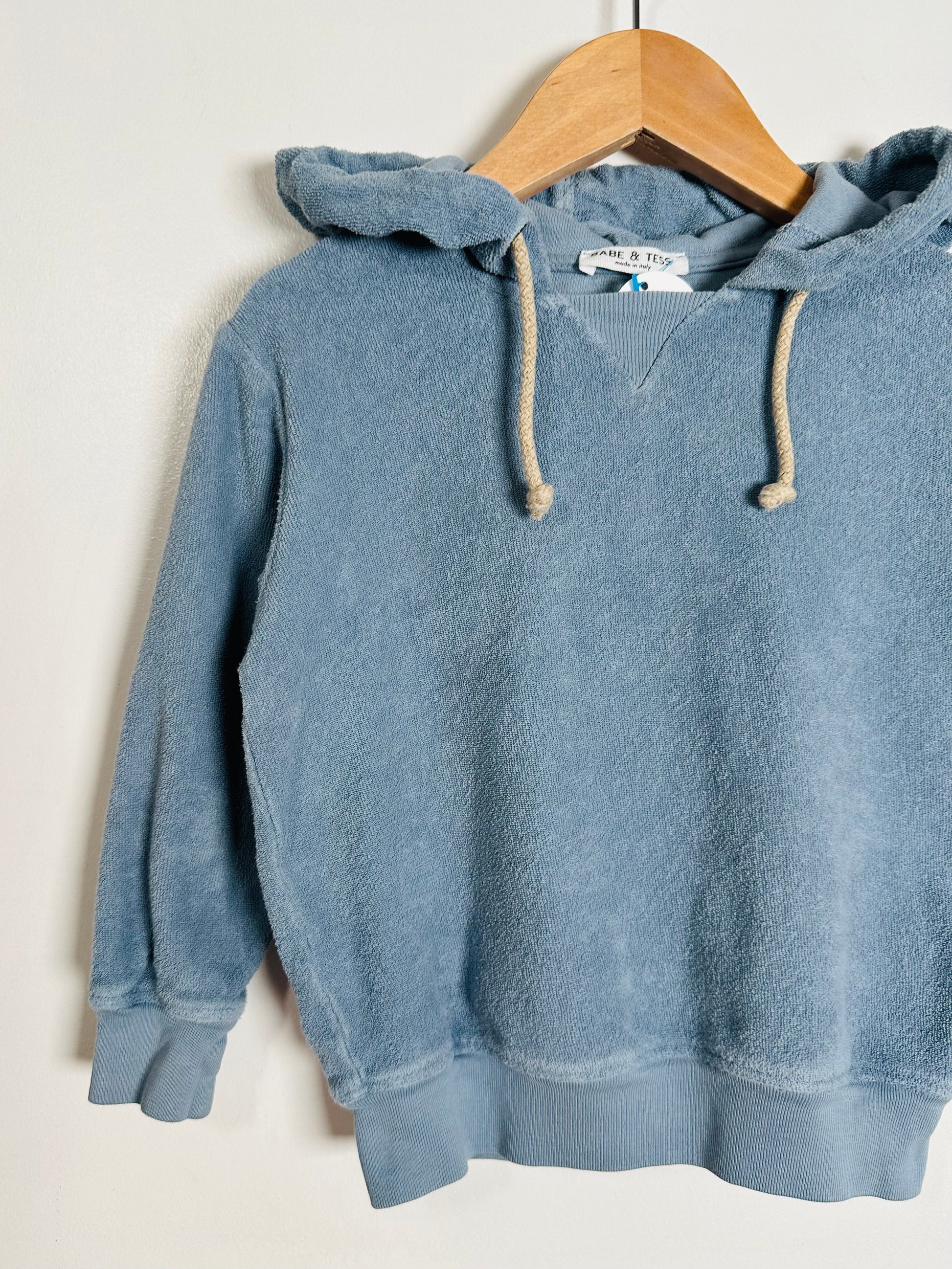 Blue hoodie on a wooden hanger against a white background