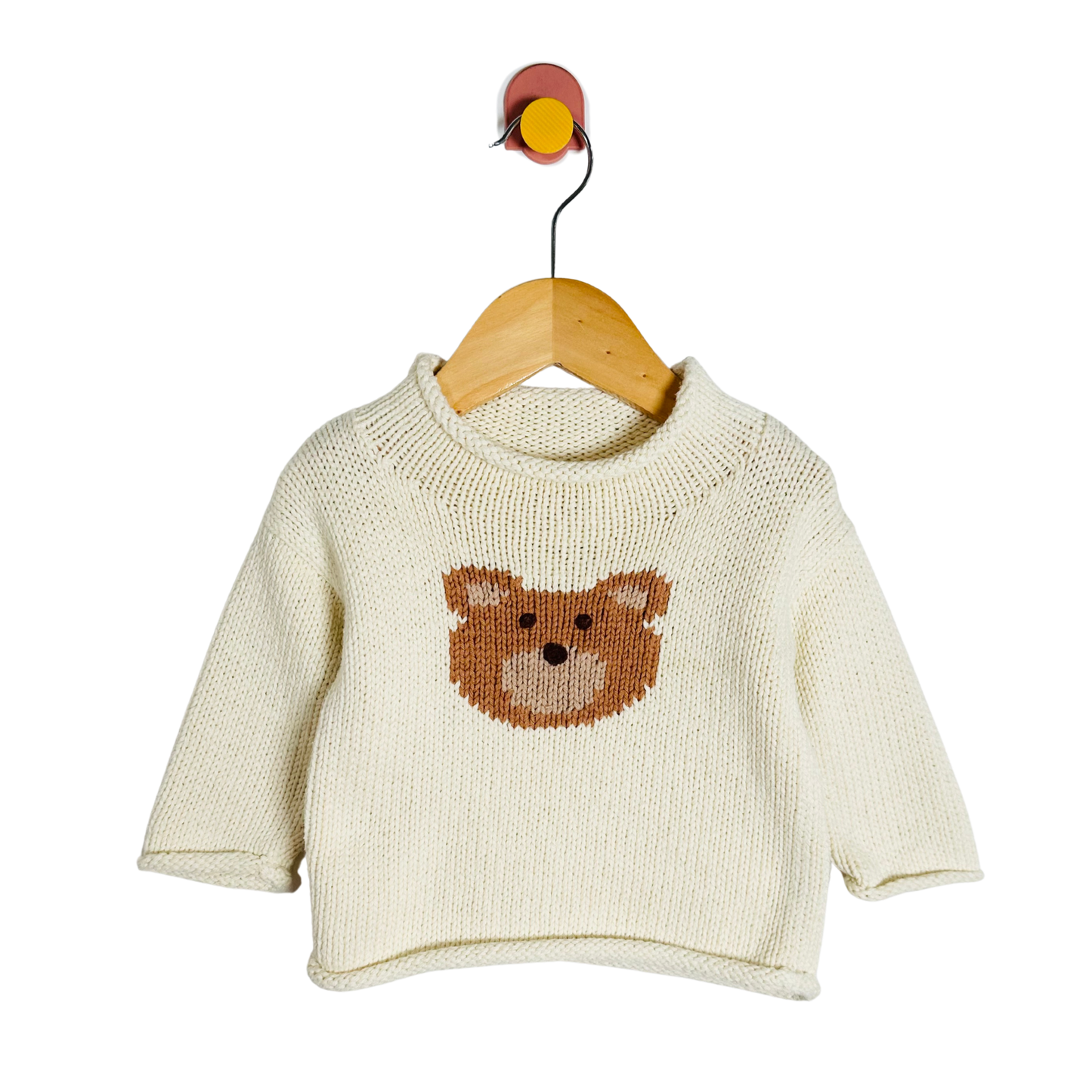 Baby sweater with bear design on a hanger against a white background