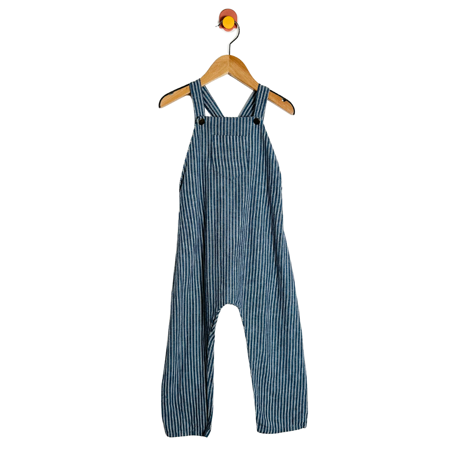 Blue striped overalls hanging on a wooden hanger against a white background