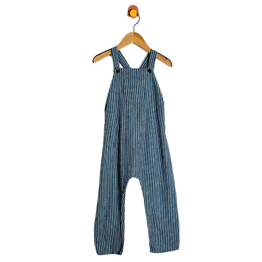 Blue striped overalls hanging on a wooden hanger against a white background