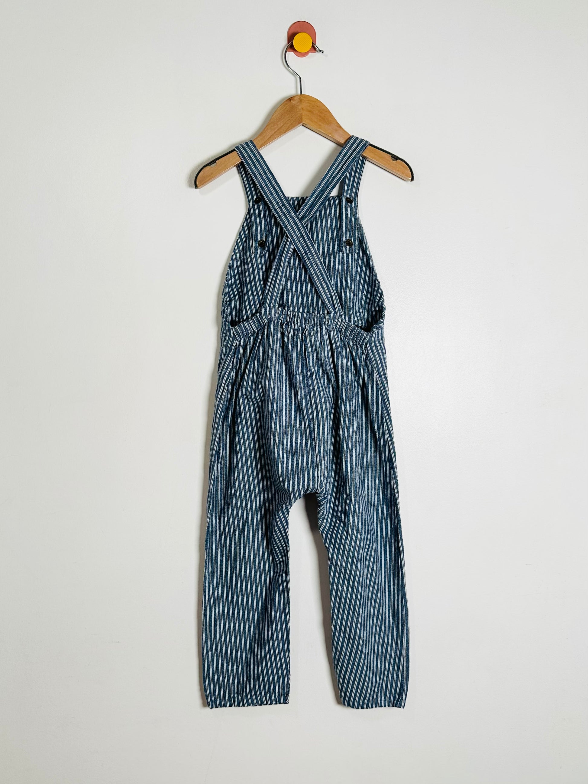 Blue striped overalls on a hanger against a white background