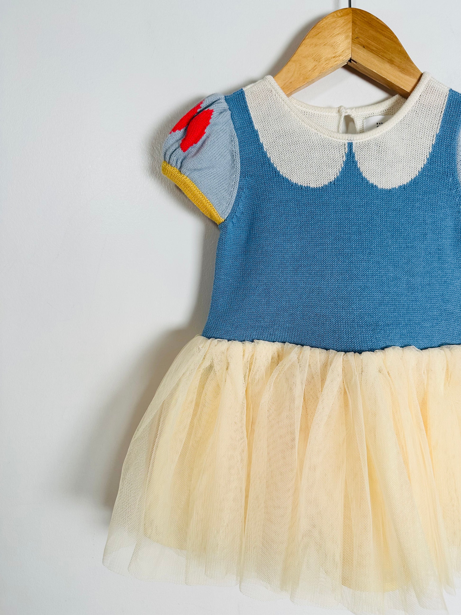 Children's dress with blue top and yellow skirt on a hanger against a white background