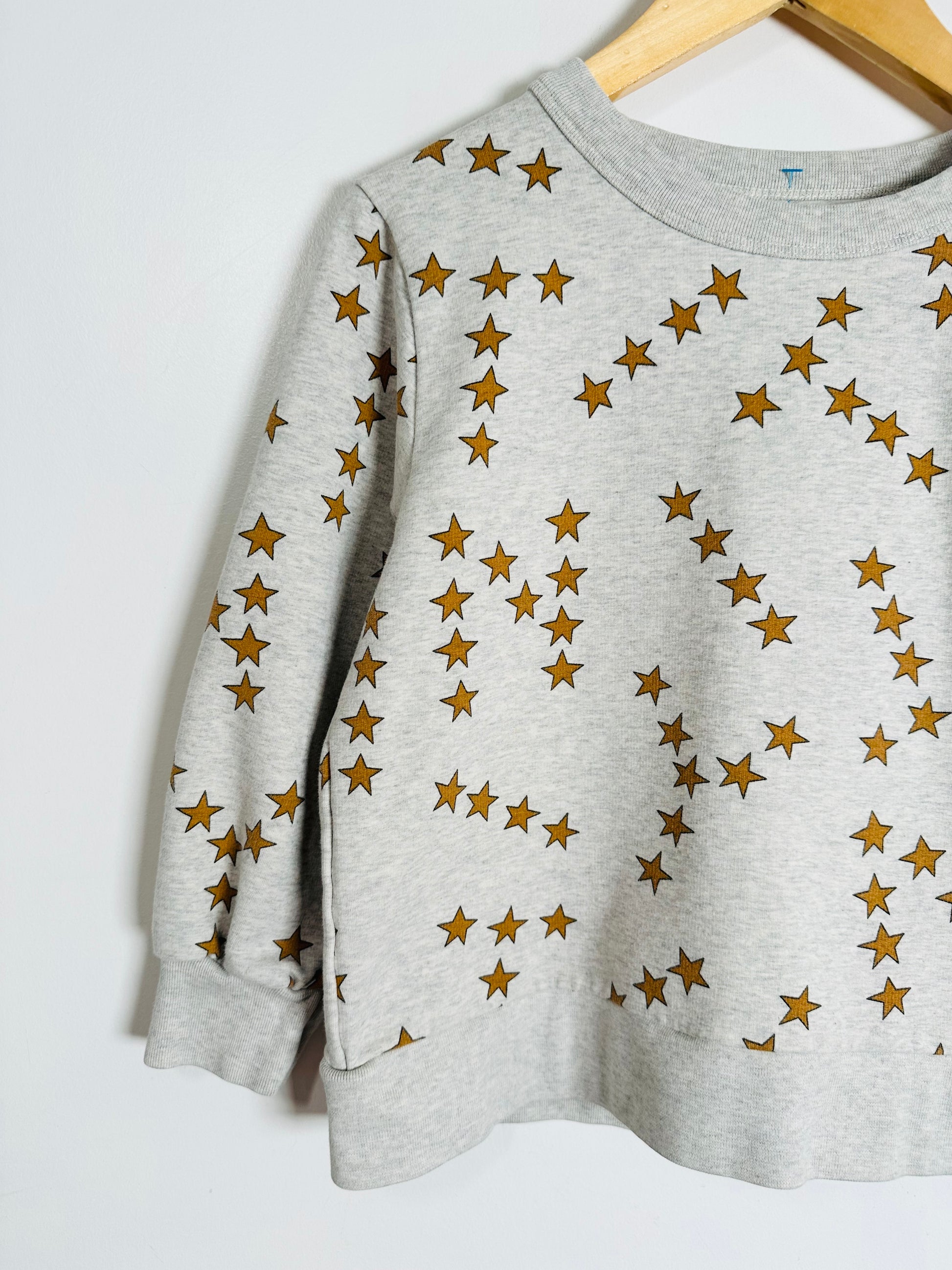 Gray sweatshirt with gold star pattern on a white background