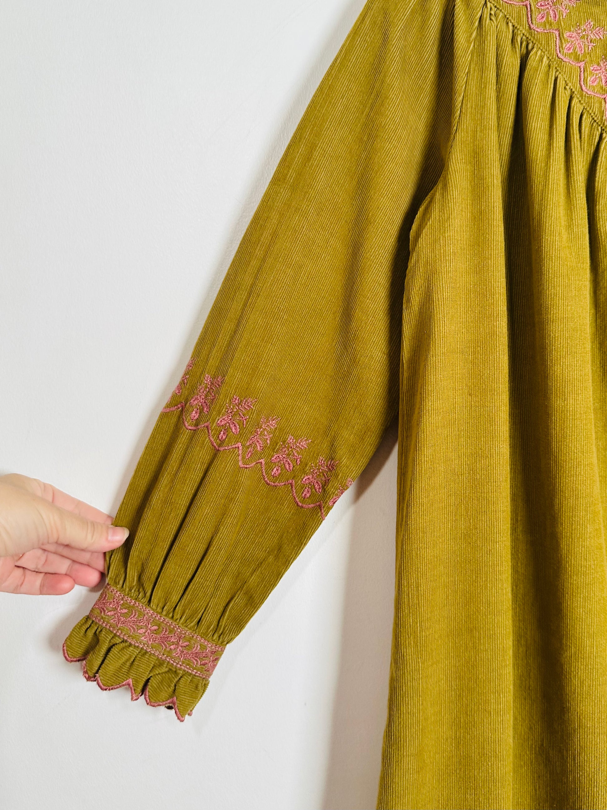 Green dress with embroidered details on a white background