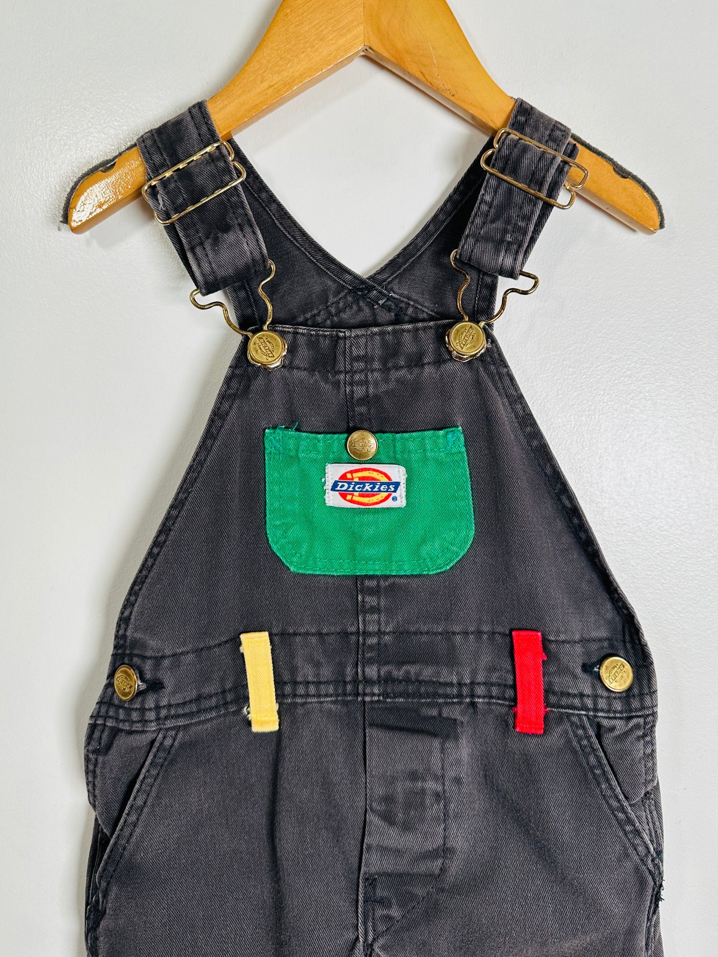 Black denim overalls with a green pocket and Dickies logo on a white background