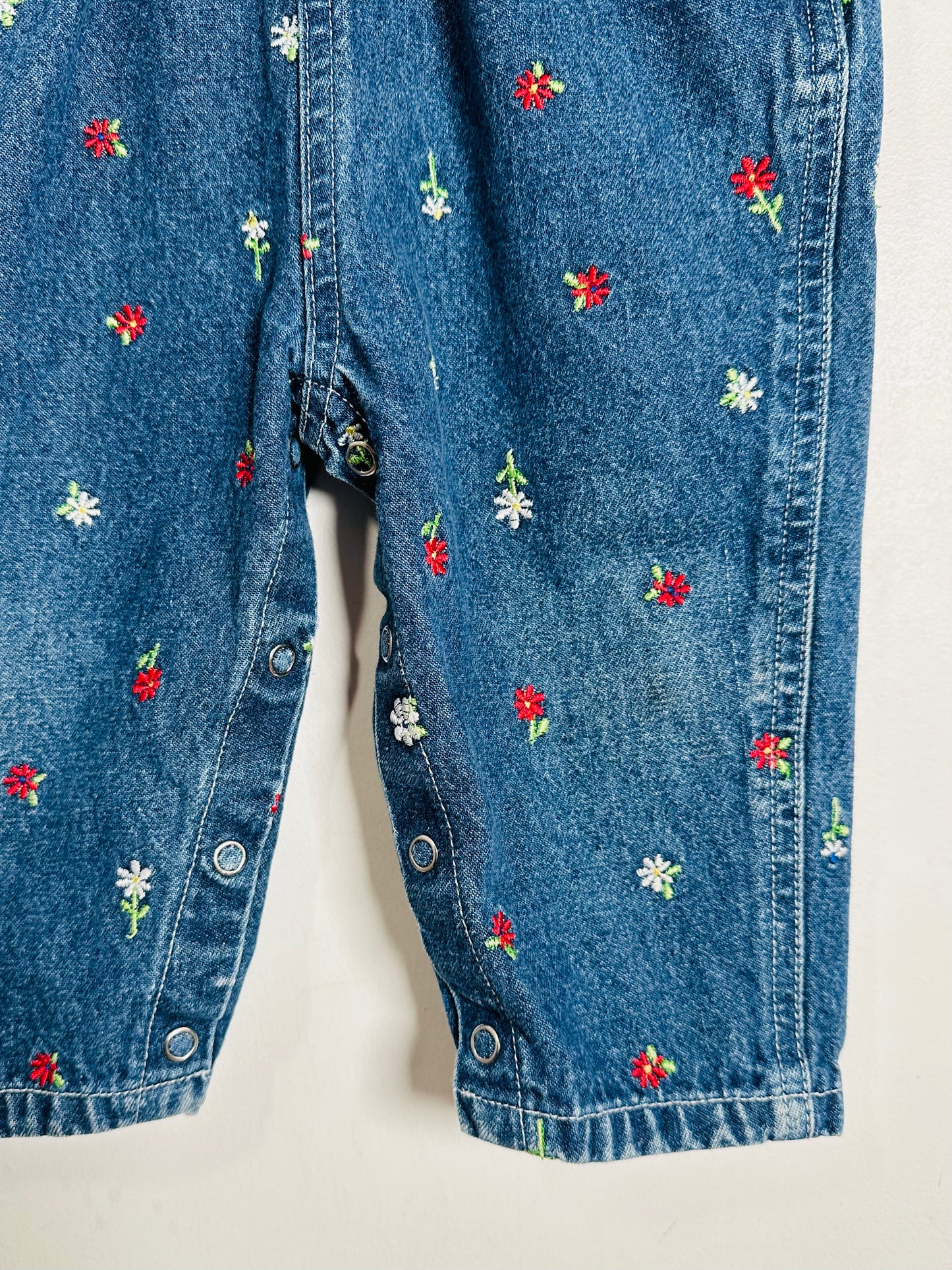Close-up of blue denim shorts with floral embroidery on a white background