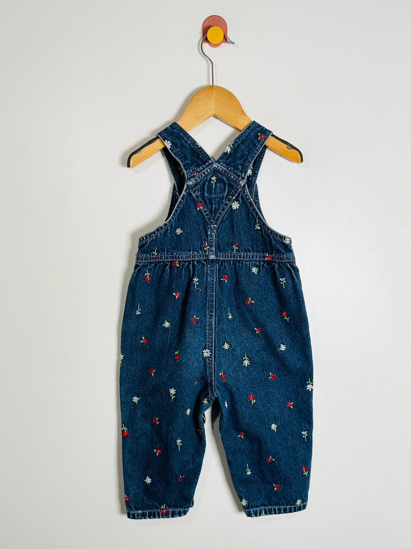 Blue denim overalls with floral patterns on a white background