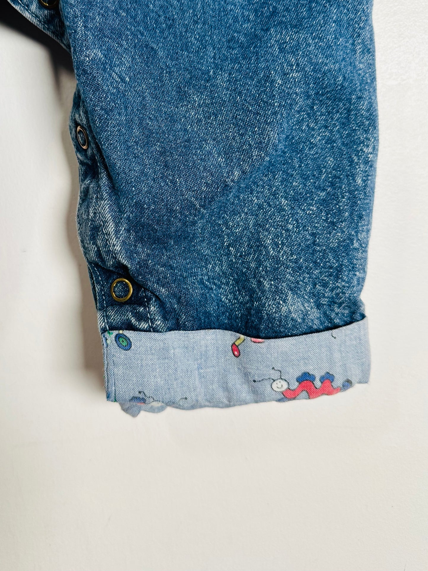 Close-up of blue denim fabric with a patterned hem on a light gray background