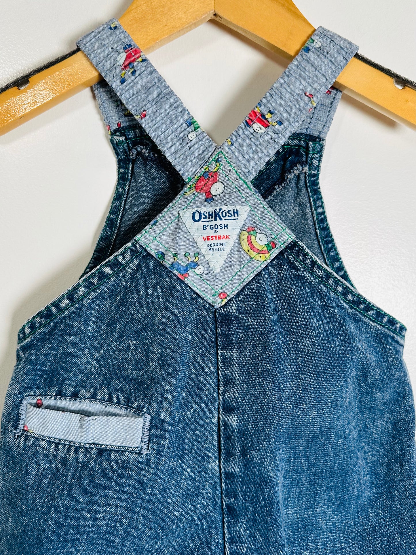Blue denim overalls with a visible brand tag on a white background
