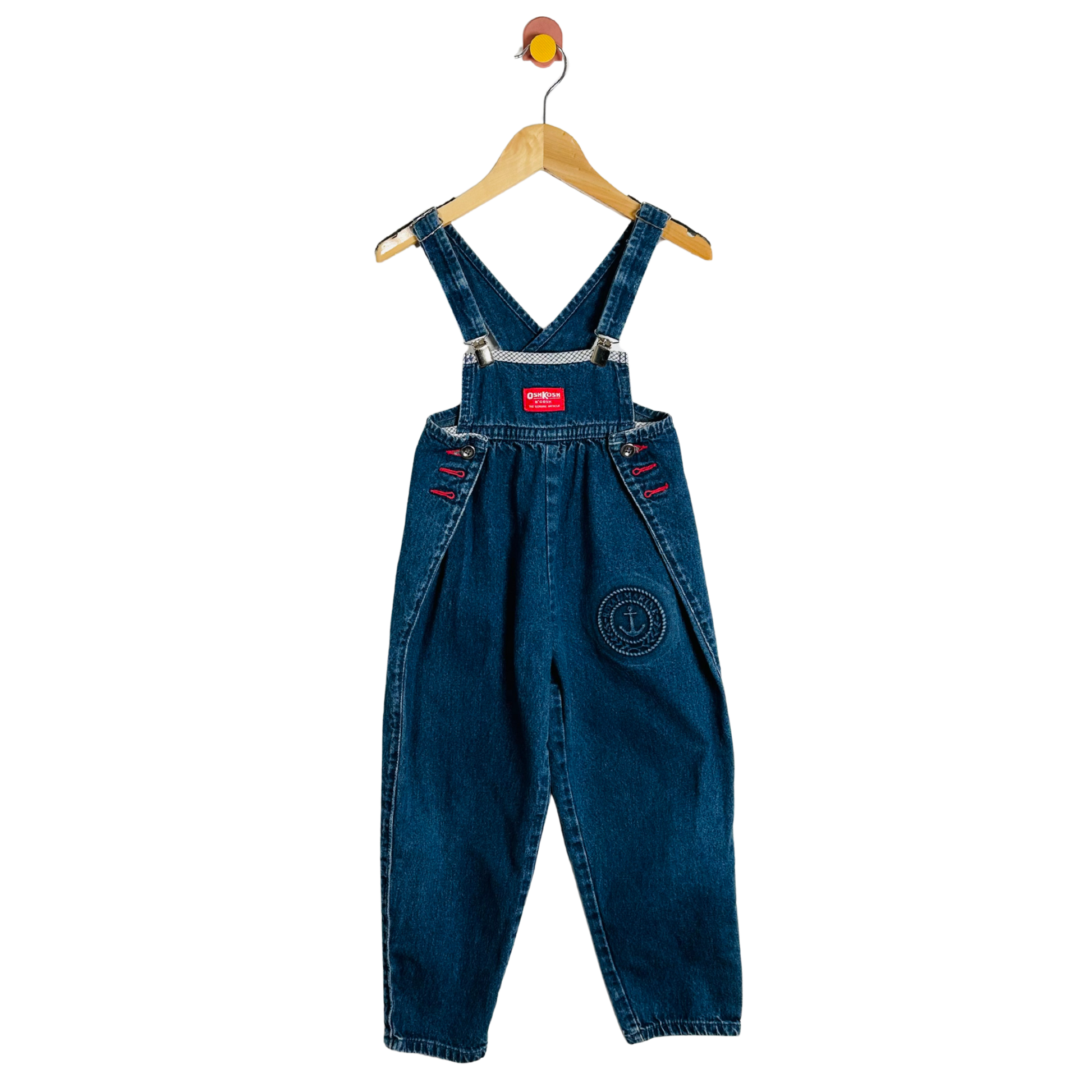 Blue denim overalls on a hanger against a white background