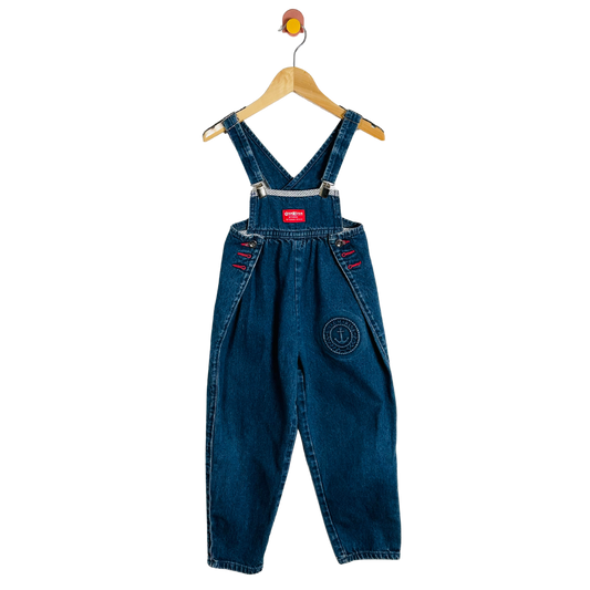 Blue denim overalls on a hanger against a white background