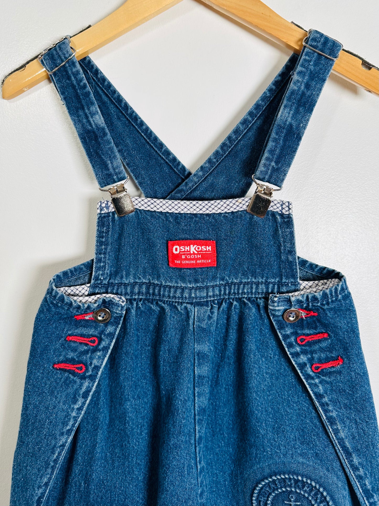 Blue denim overalls with a visible brand label on a white background
