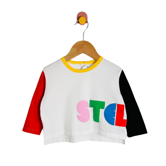 White crop top with colorful letters on a wooden hanger against a white background