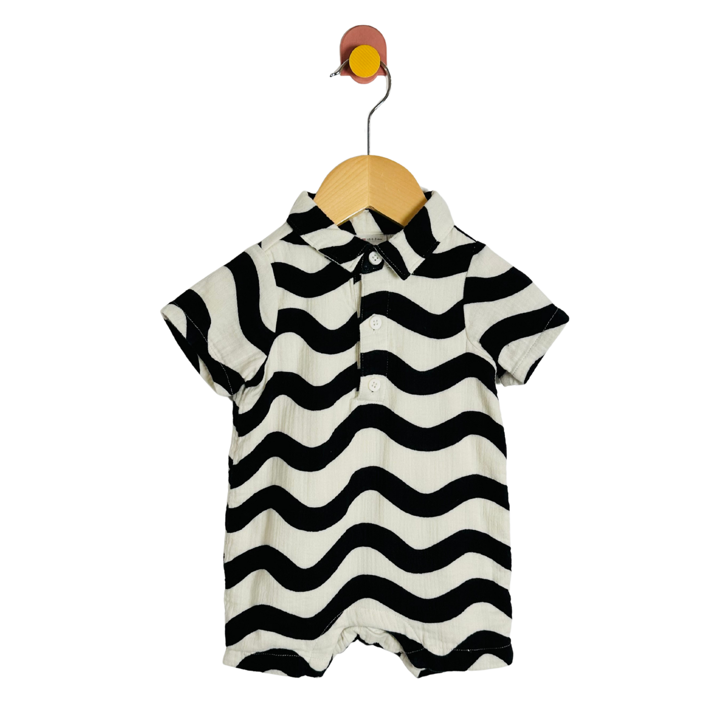 Black and white striped baby romper on a wooden hanger against a white background
