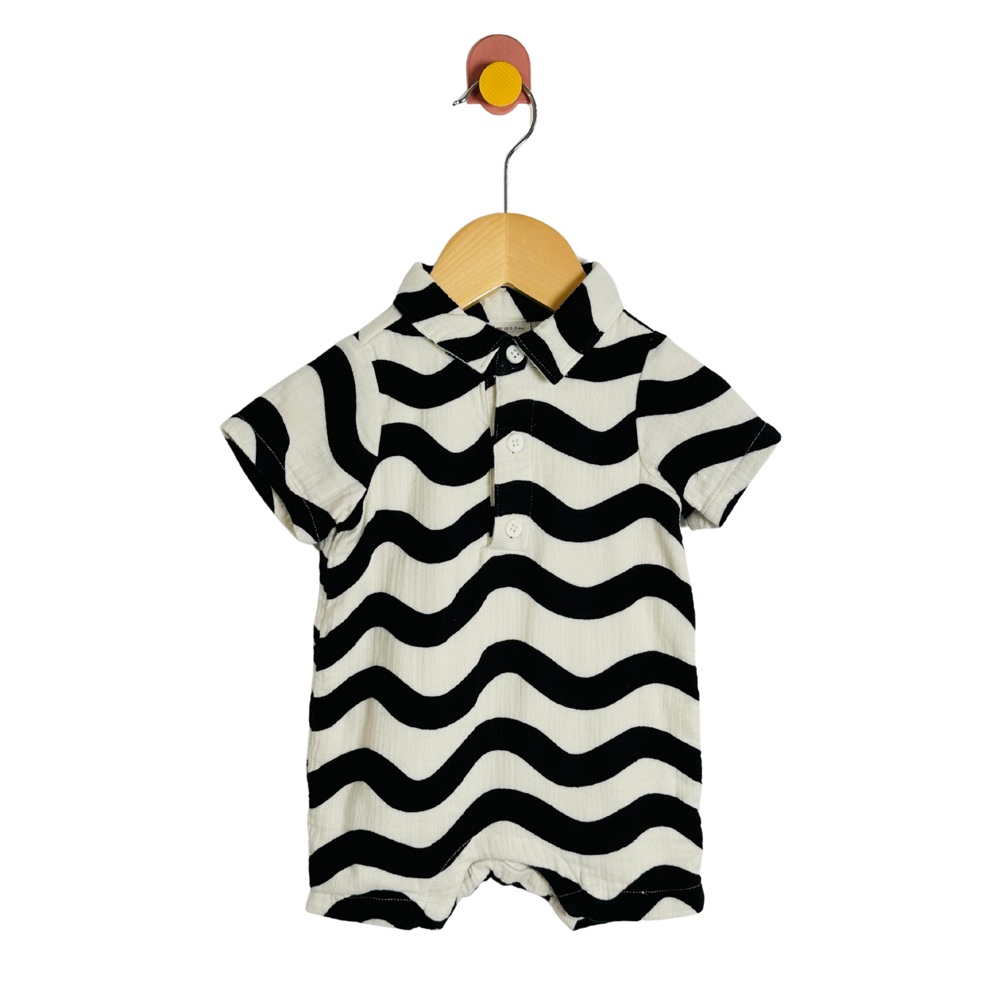Black and white striped baby romper on a wooden hanger against a white background