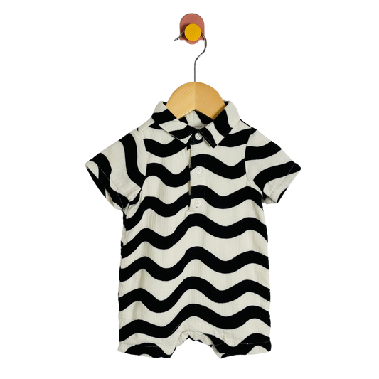 Black and white striped baby romper on a wooden hanger against a white background