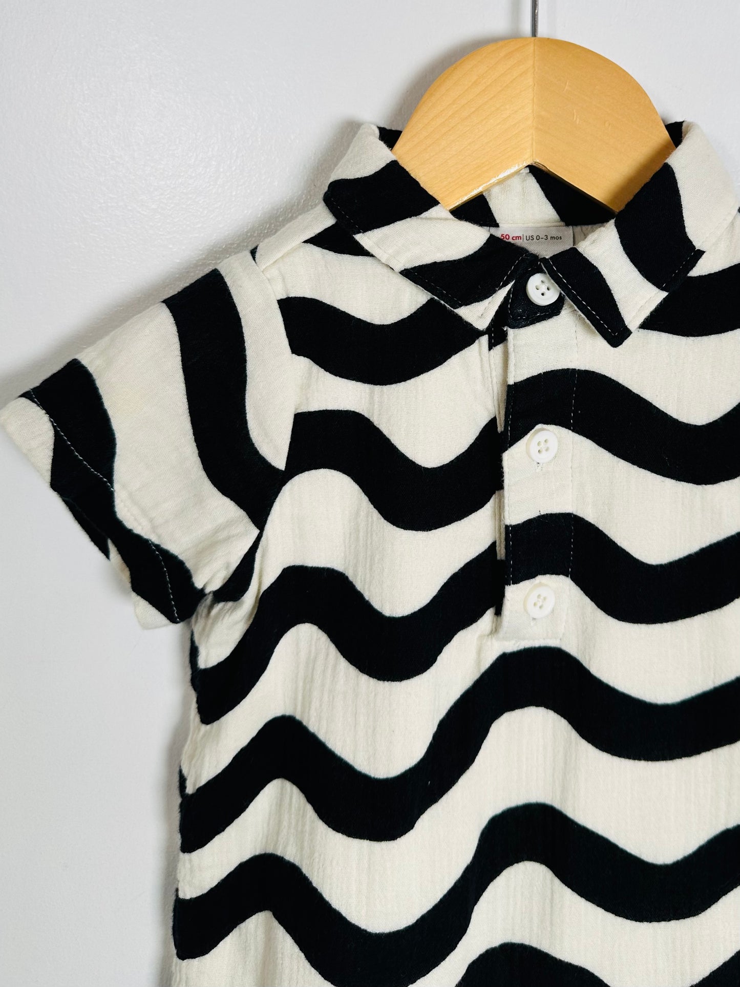 Black and white striped shirt on a wooden hanger against a light gray background