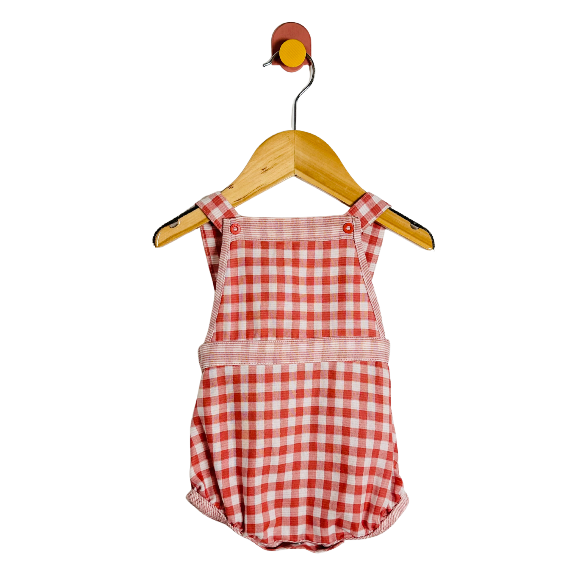Red and white checkered romper on a wooden hanger against a white background