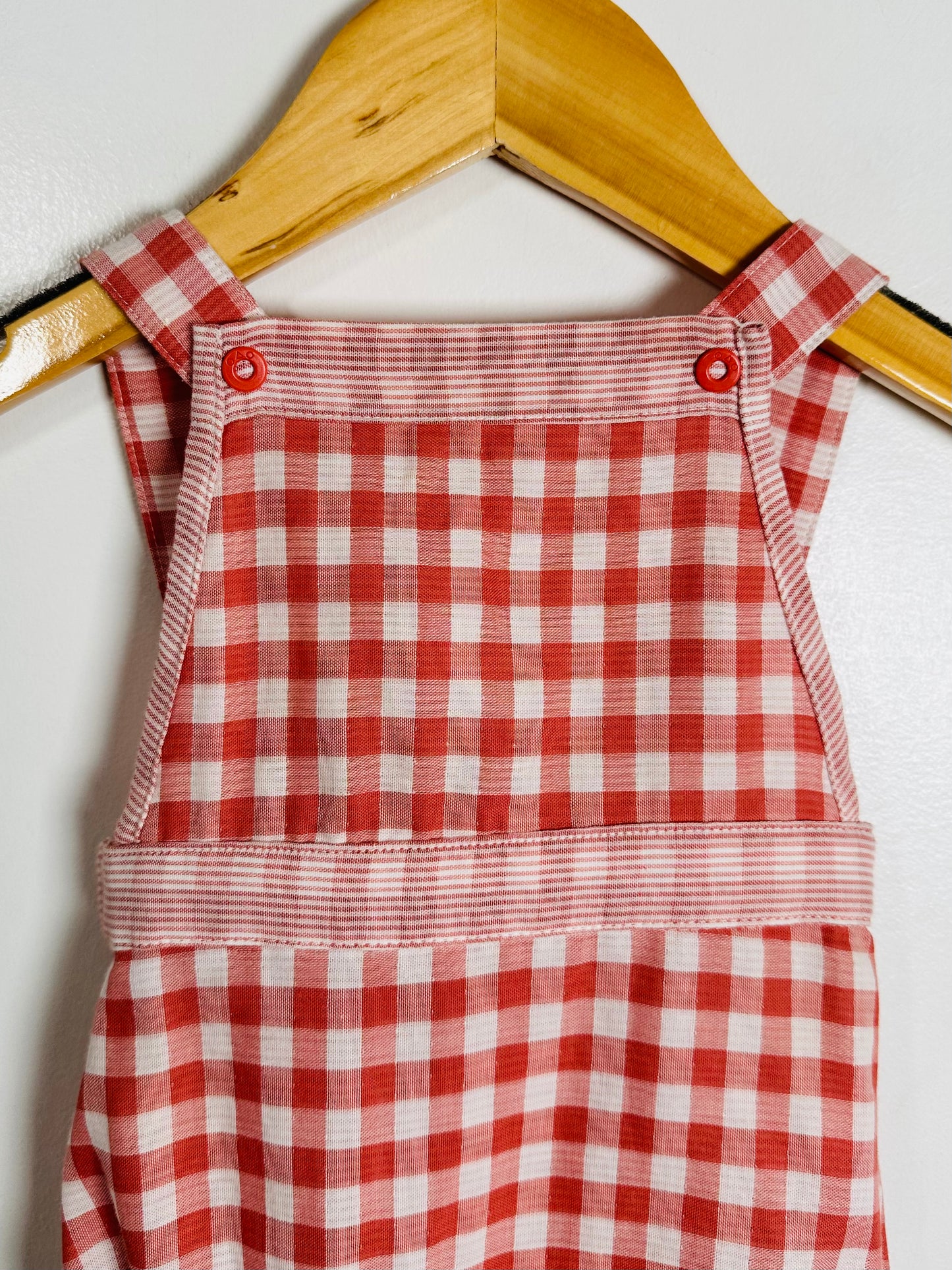 Red and white checkered dress on a wooden hanger against a white background
