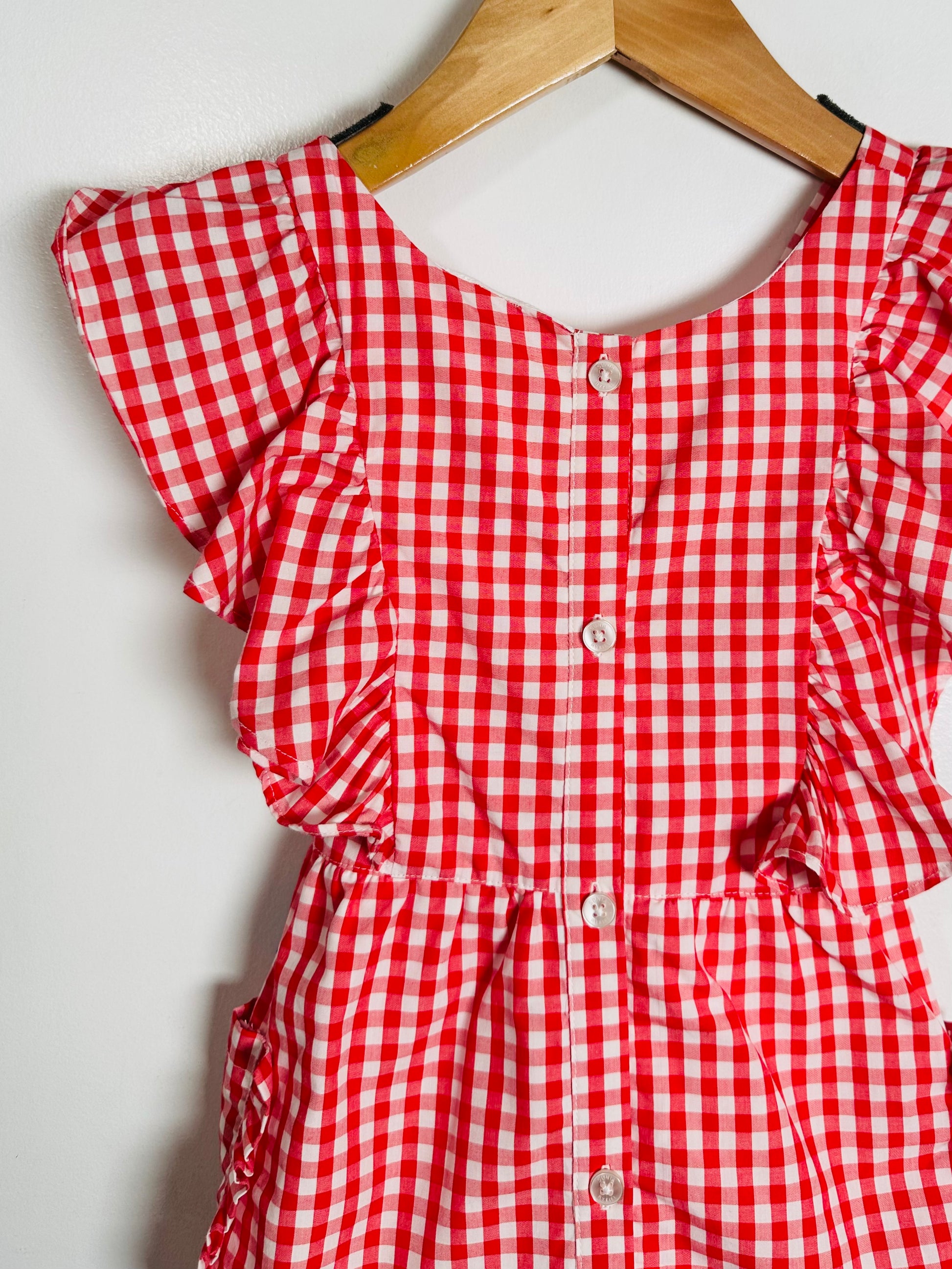 Red and white checkered dress on a hanger against a white background