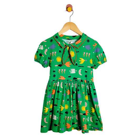 Green children's dress with colorful patterns on a hanger against a white background
