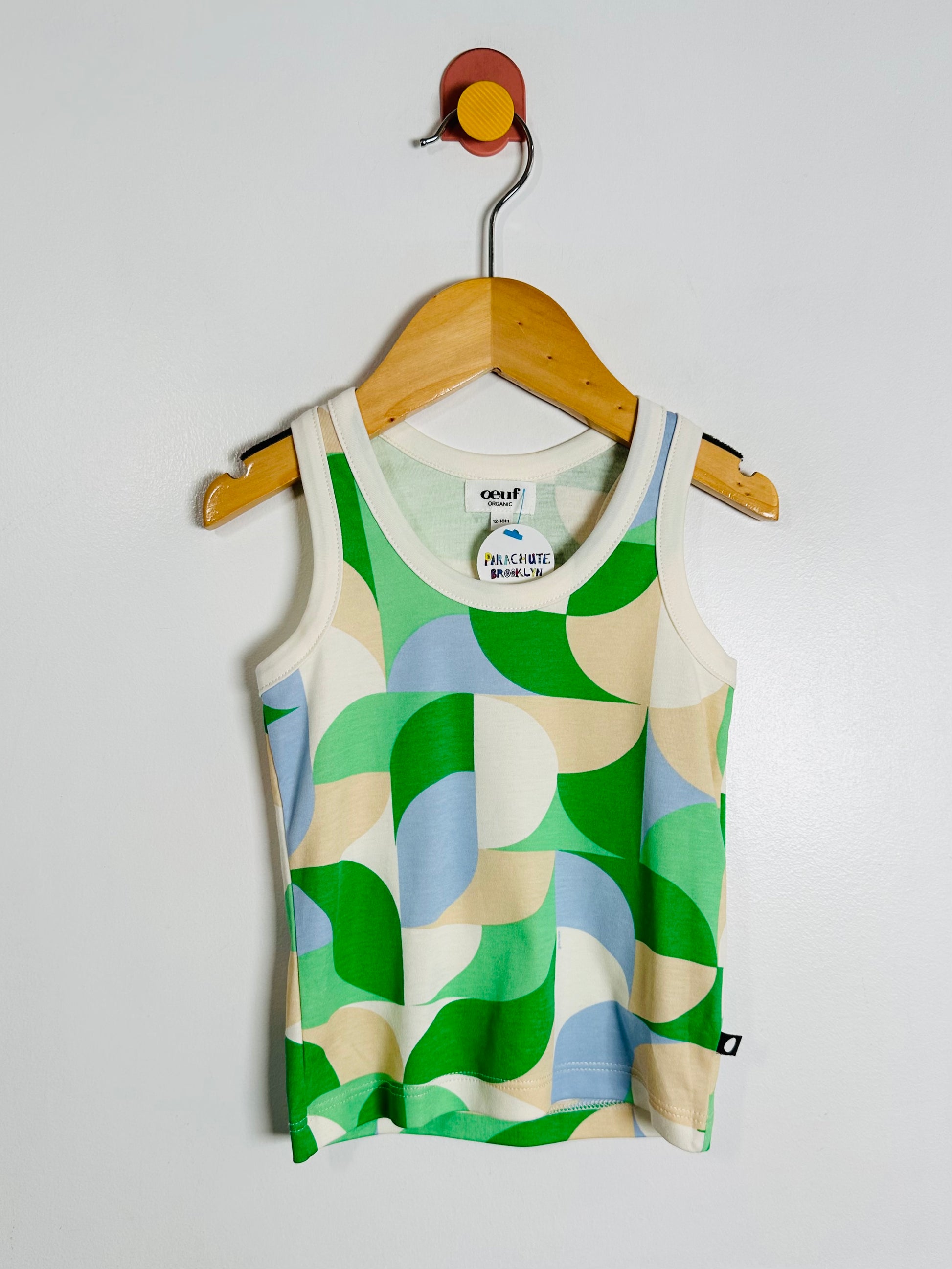 Colorful tank top with geometric pattern on a wooden hanger against a white background