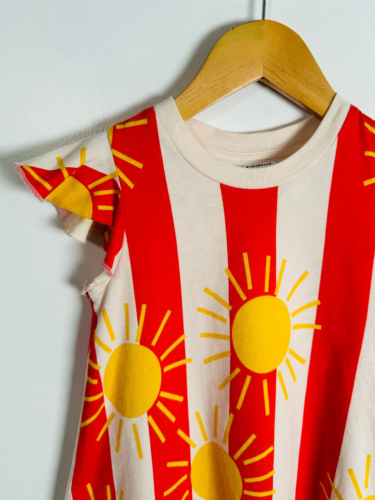 Children's dress with sun pattern on a hanger against a white background