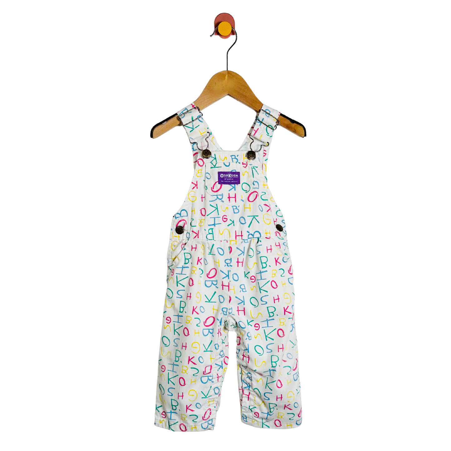 Children's overalls with colorful letter pattern on a hanger against a white background
