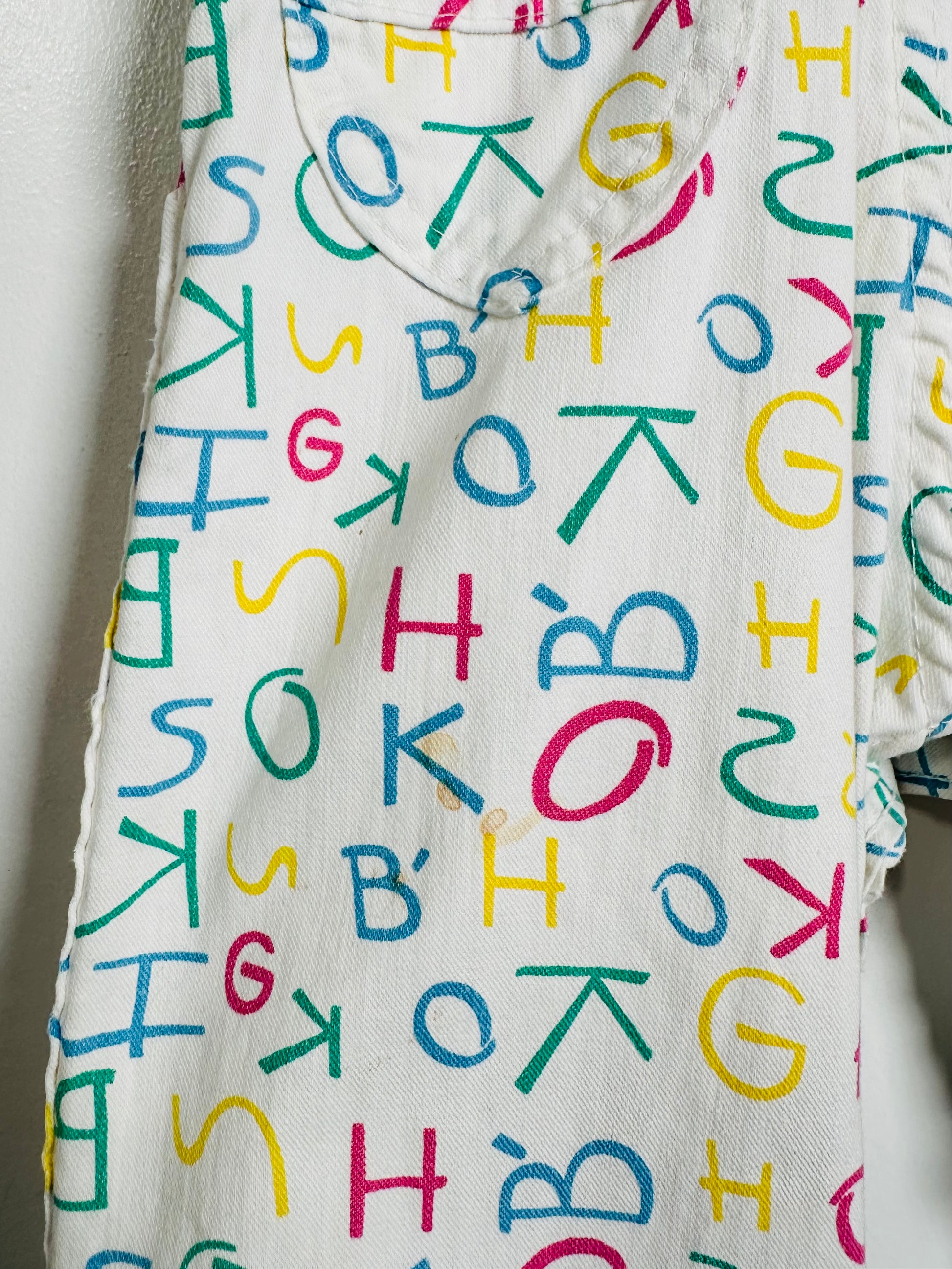 Baby outfit with colorful letter pattern on a plain background