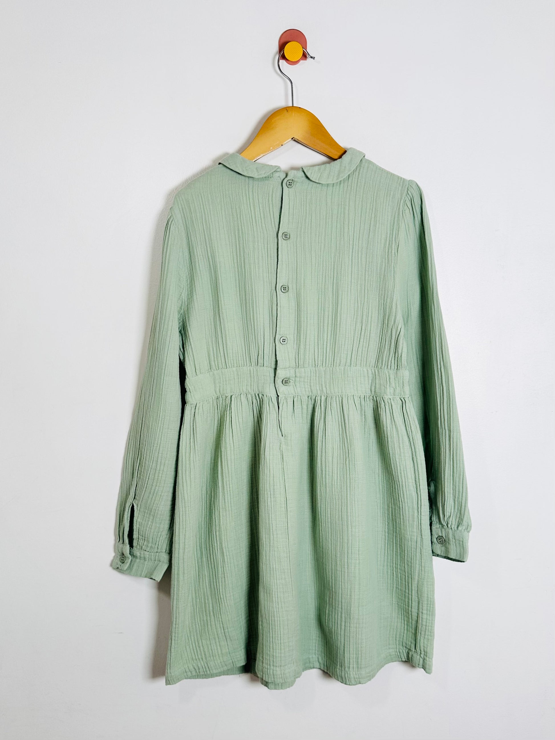 Green dress on a hanger against a white background