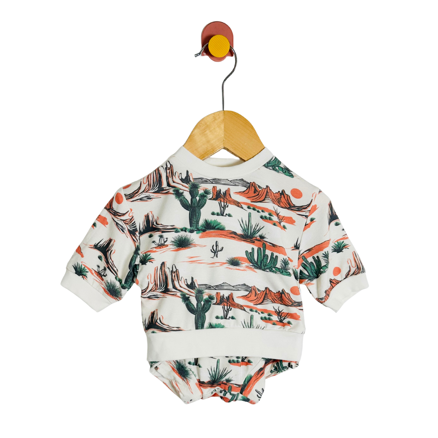 Baby onesie with desert pattern on a hanger against a white background