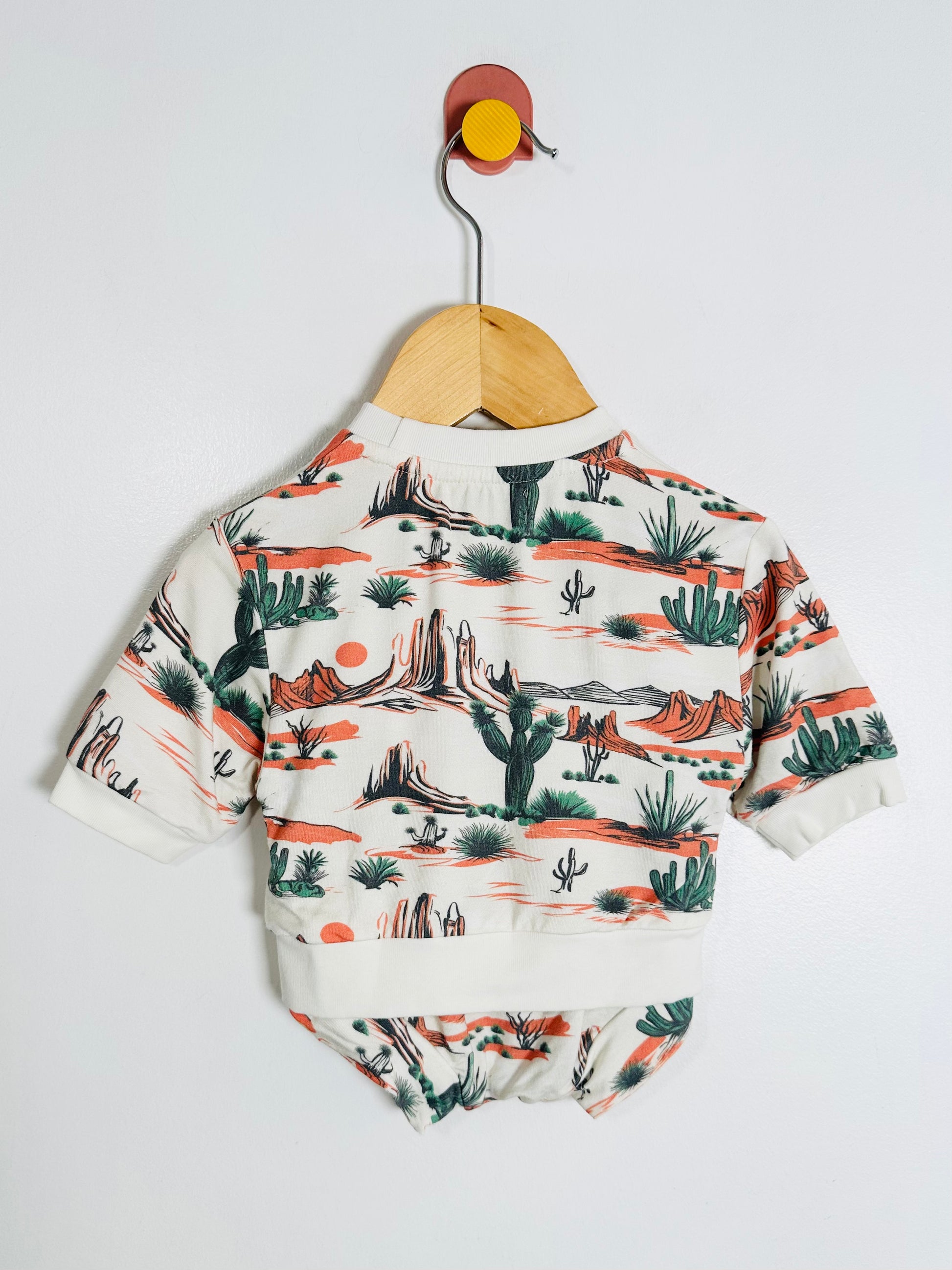 Baby romper with desert landscape print on a white background