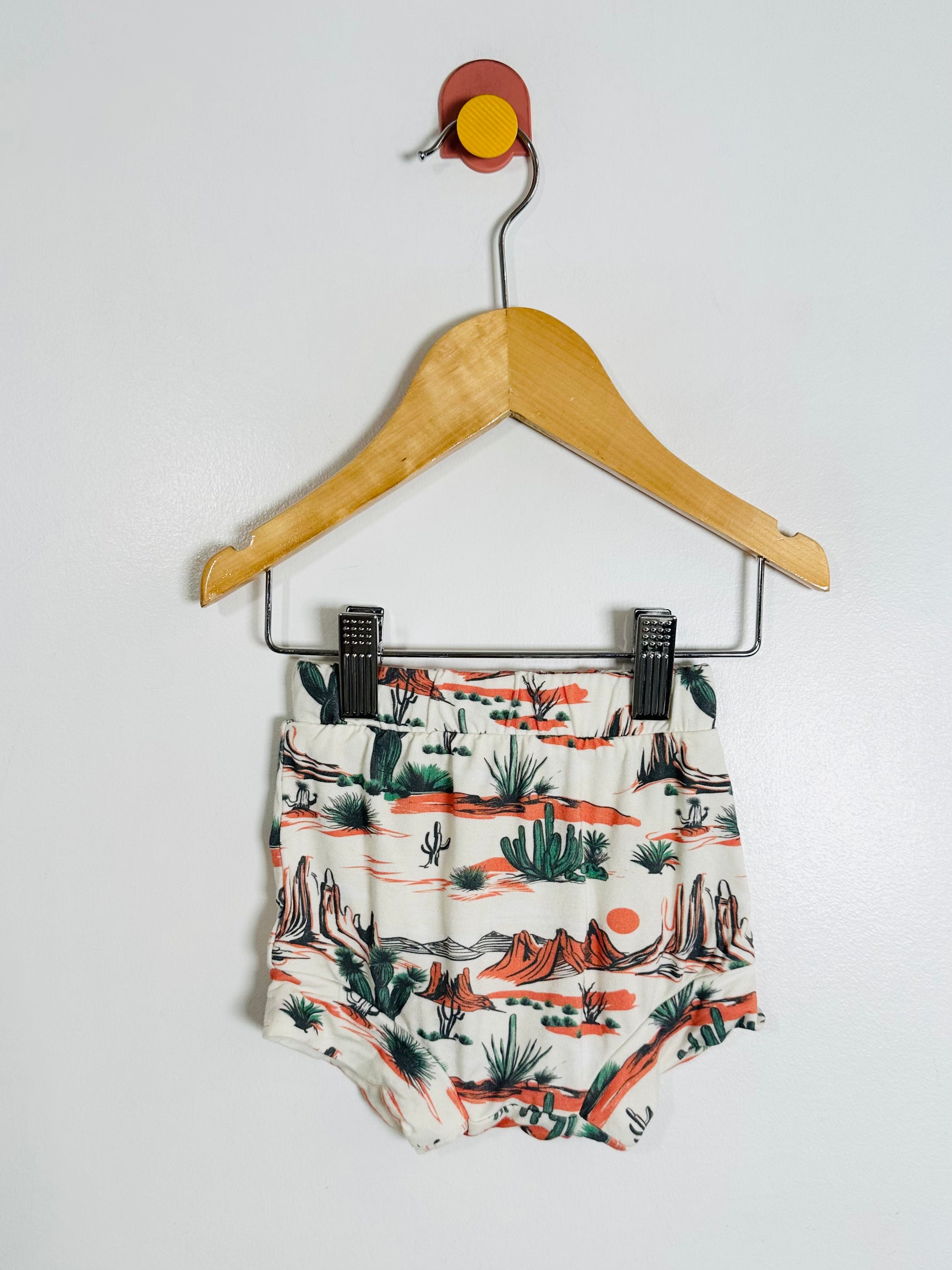 Children's shorts with a nature print on a hanger against a white background