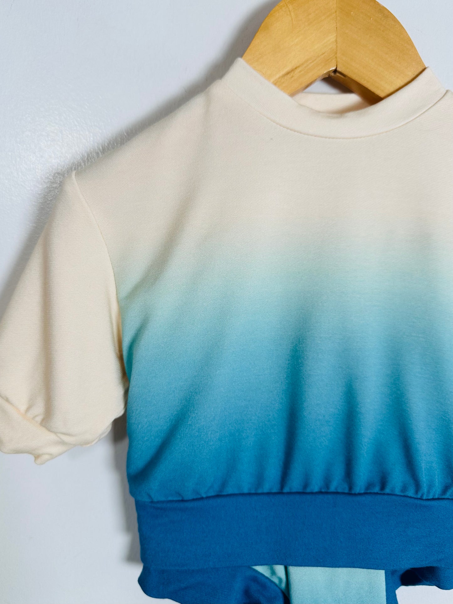 Gradient top from beige to blue on a hanger against a light background