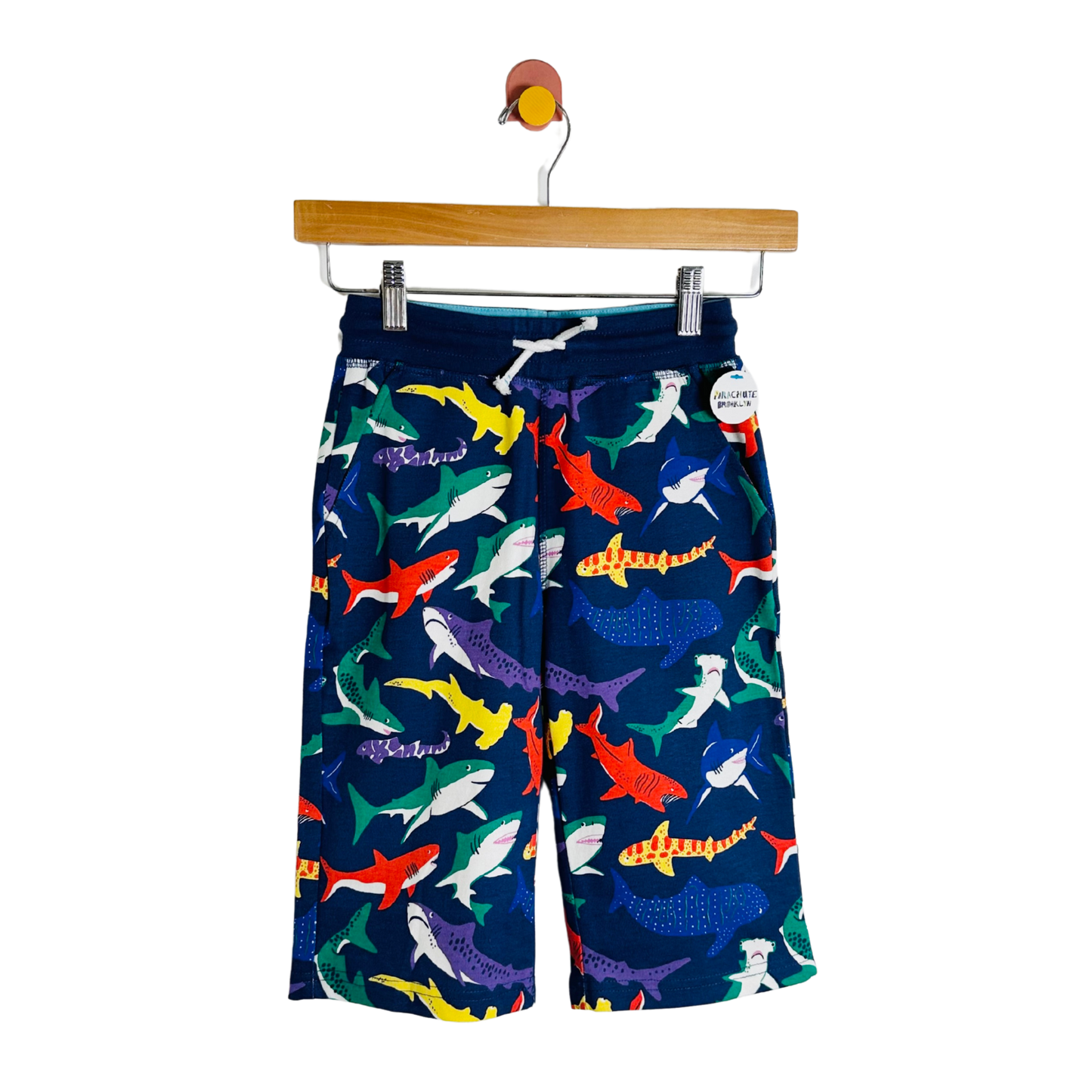 Colorful shark-patterned shorts on a hanger against a white background