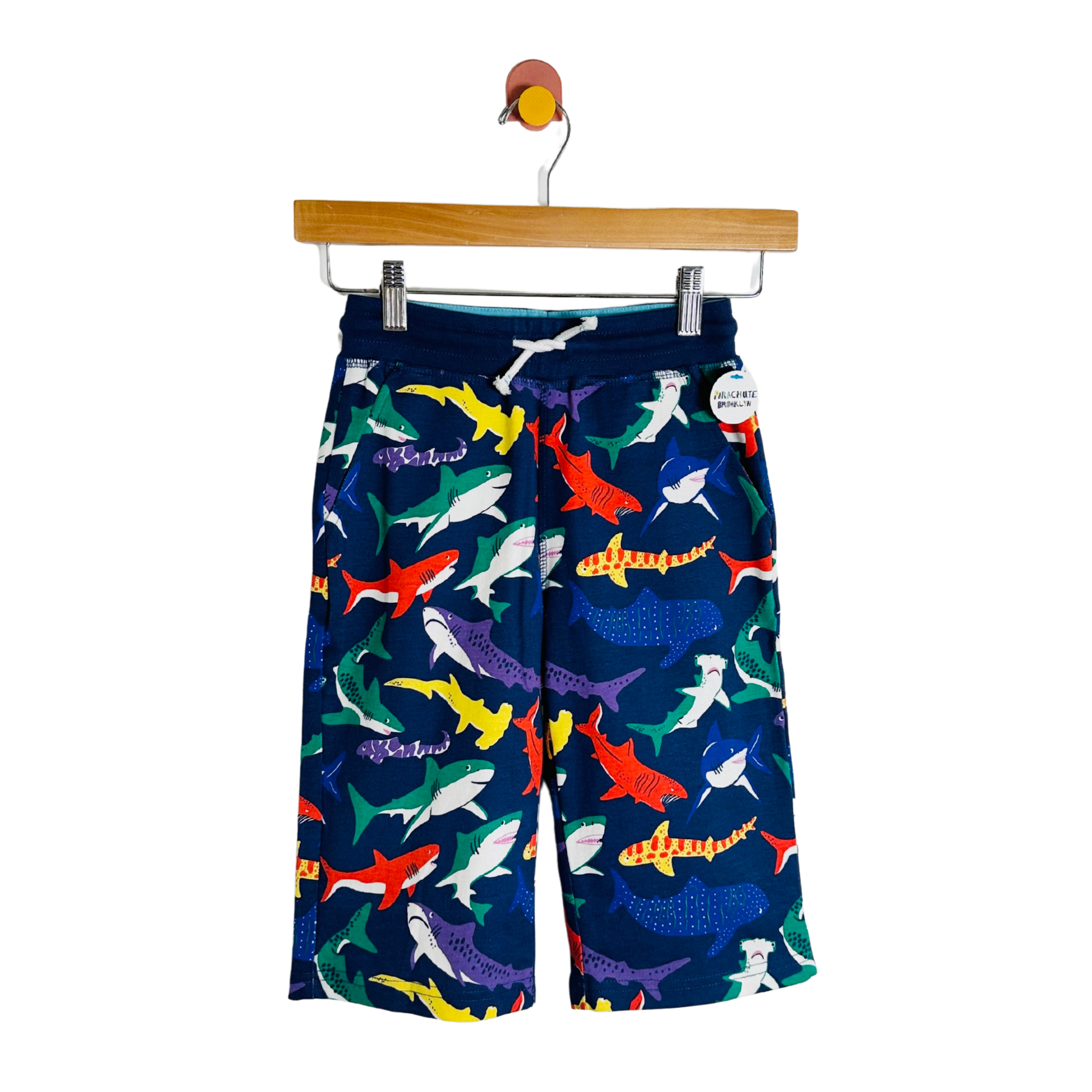 Colorful shark-patterned shorts on a hanger against a white background
