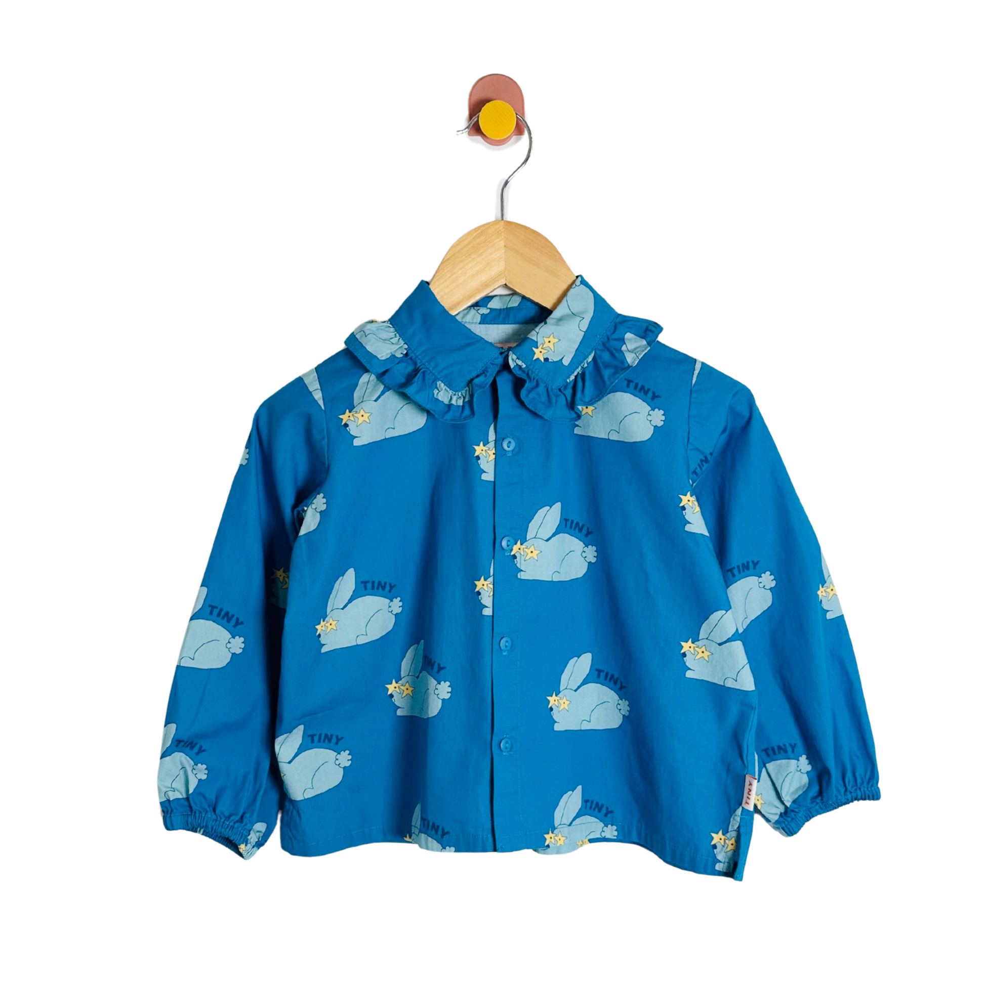 Blue children's top with animal prints on a wooden hanger against a white background