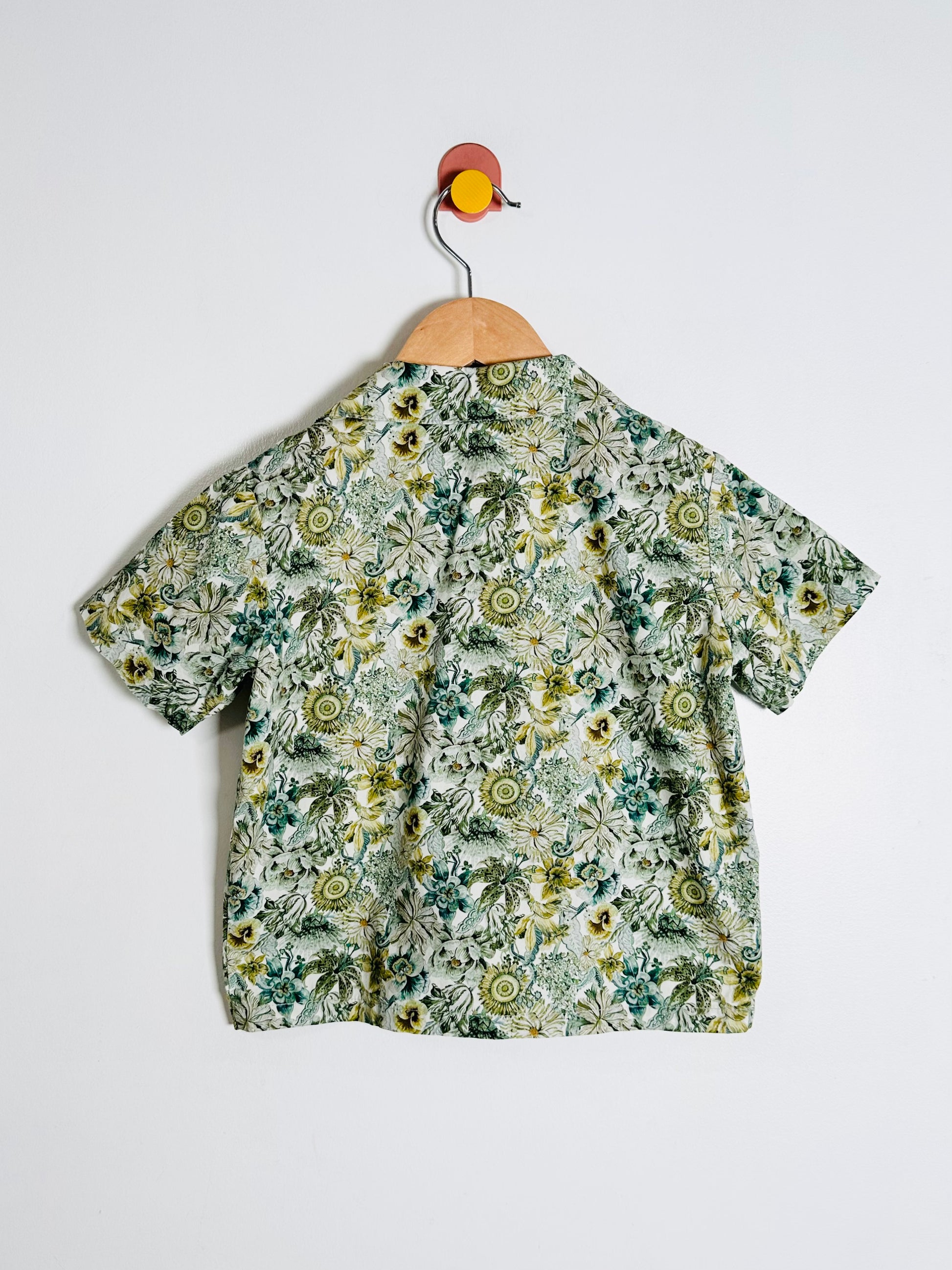 Floral patterned shirt on a hanger against a white background