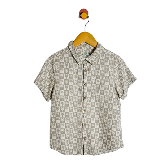 Short-sleeve shirt with palm tree pattern on a hanger against a white background