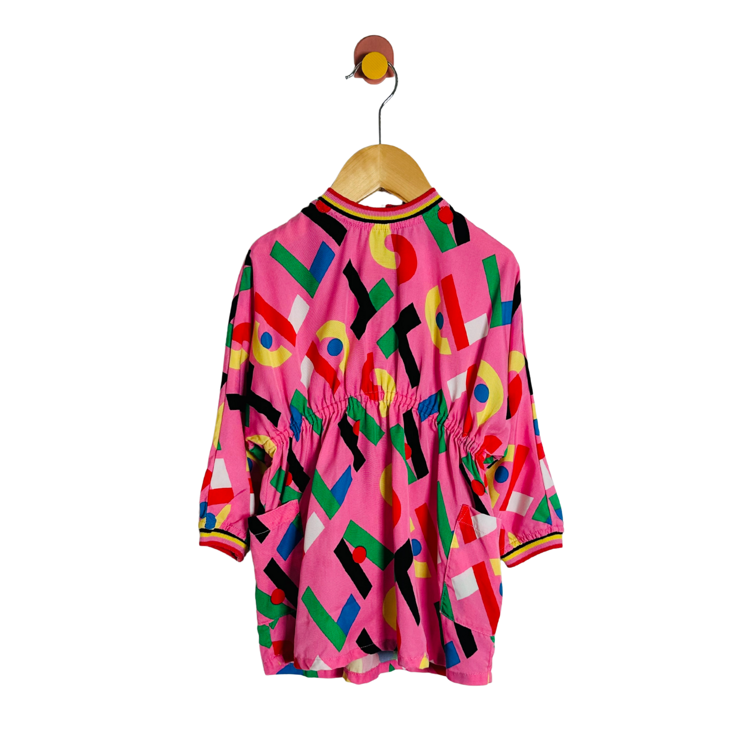 Colorful geometric-patterned dress on a hanger against a white background