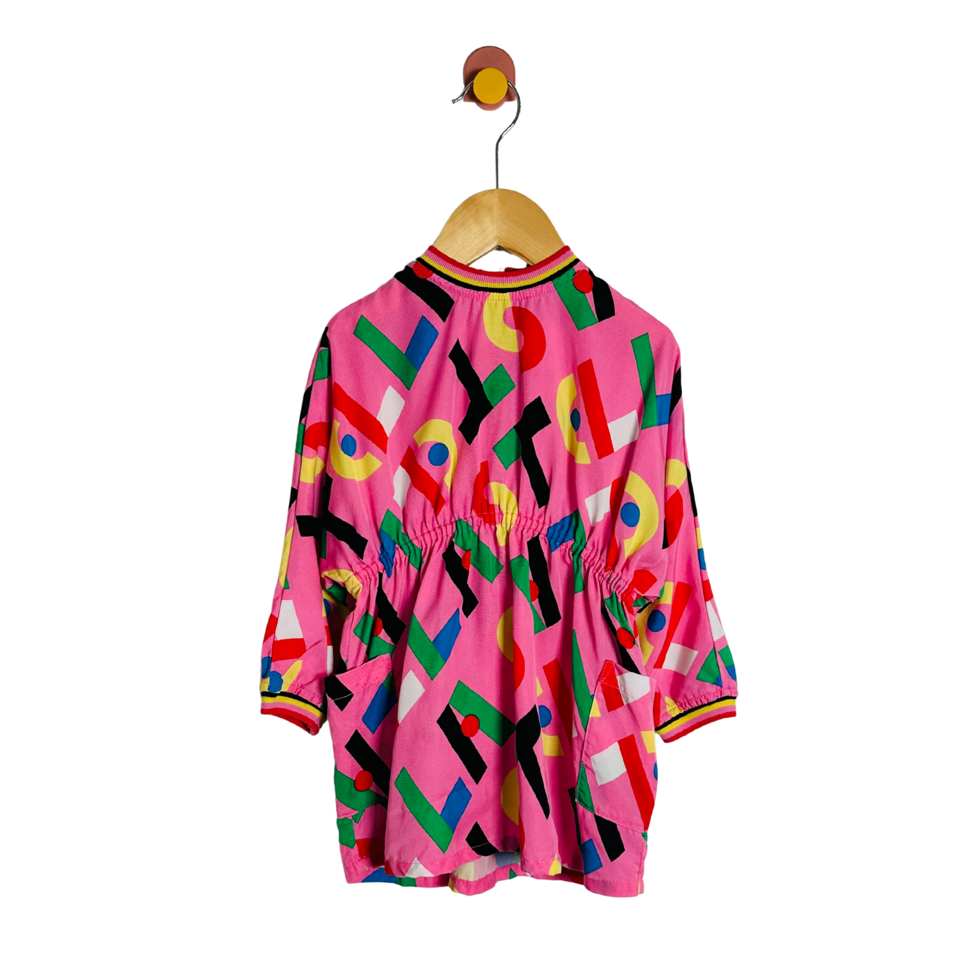 Colorful geometric-patterned dress on a hanger against a white background