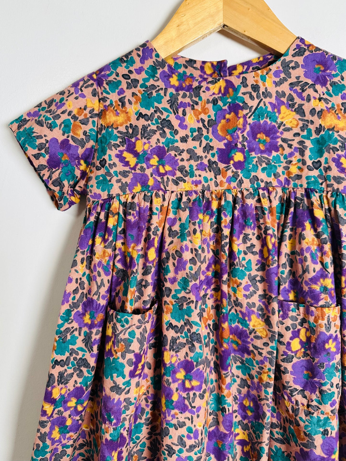 Floral patterned dress on a hanger against a white background
