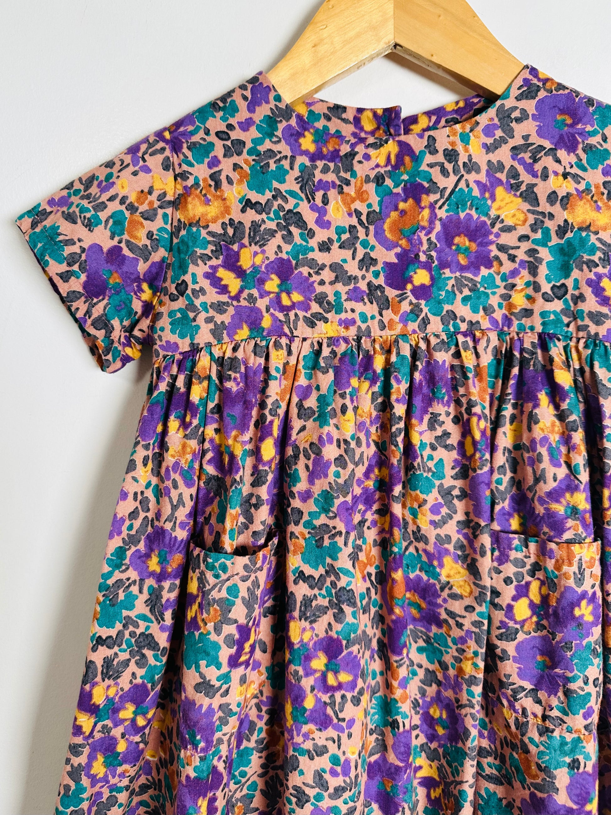Floral patterned dress on a hanger against a white background