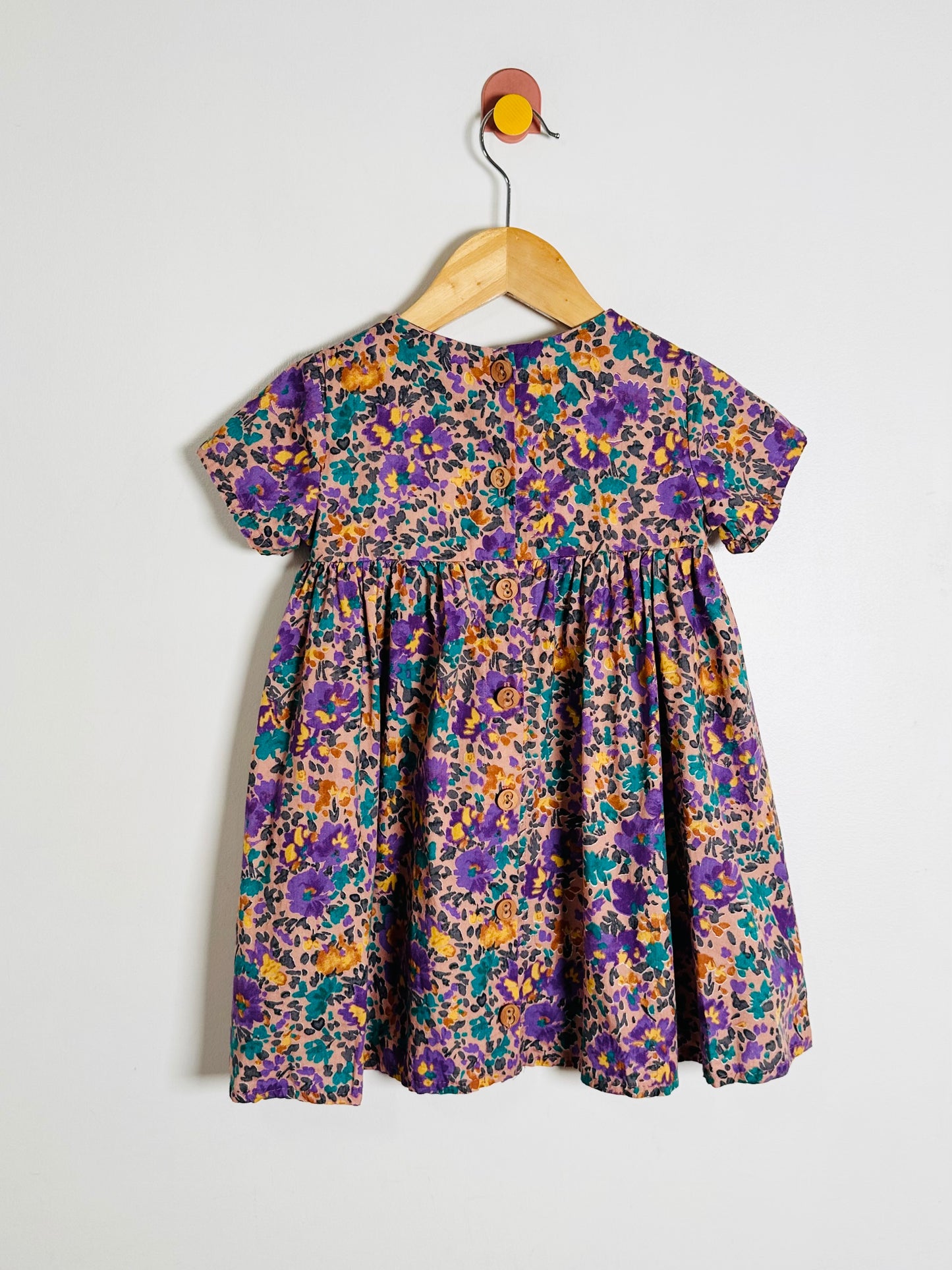 Floral dress on a hanger against a white background